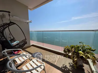 Stunning ocean view from a modern balcony with stylish seating and lush plant.