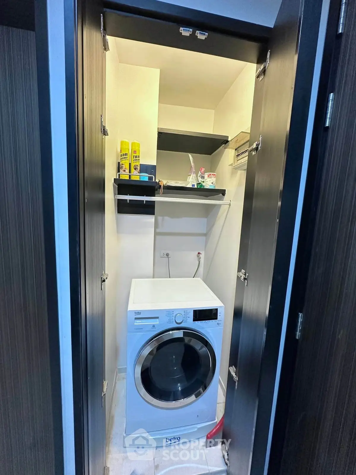 Compact laundry area with modern washing machine and storage shelves