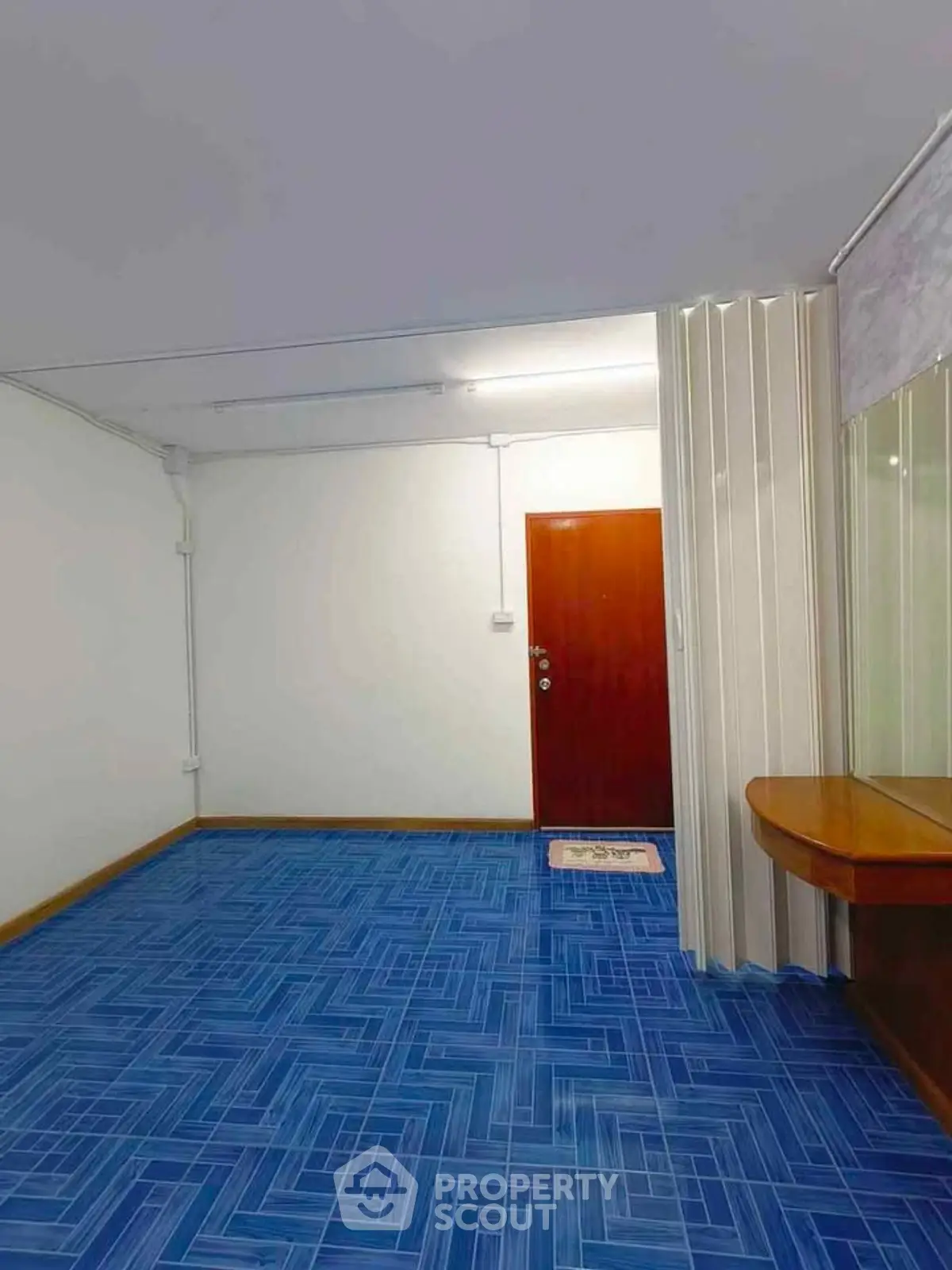 Spacious room with vibrant blue flooring and wooden door, ideal for creative interior design.