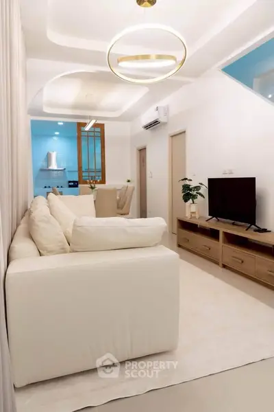 Elegant living room with modern decor and cozy white sofa, featuring stylish lighting and open layout.