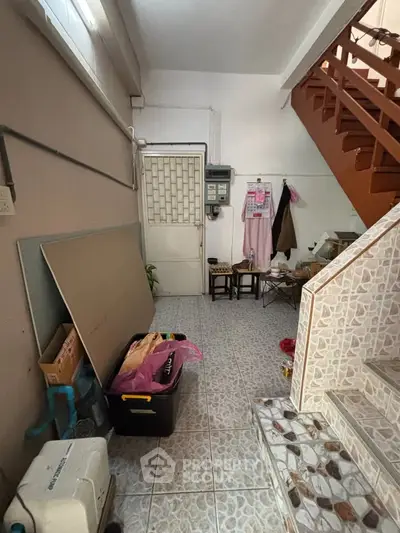 Cozy interior space with tiled flooring and staircase, ideal for storage or utility use.
