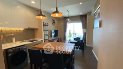 Modern open-layout kitchen and living area with stylish lighting and cozy seating.