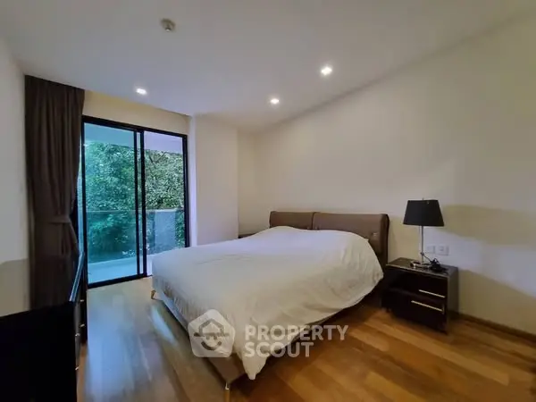 Modern bedroom with balcony view and wooden flooring in a cozy apartment.