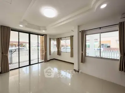 Spacious living room with large windows and modern ceiling design, perfect for natural light lovers.