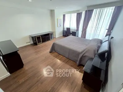 Spacious bedroom with modern decor and large windows for natural light