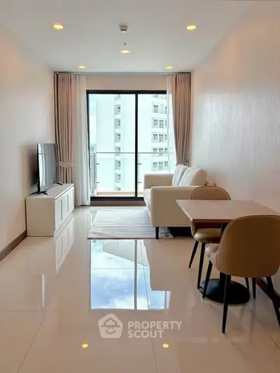 Modern living room with sleek furniture and large window offering city view.