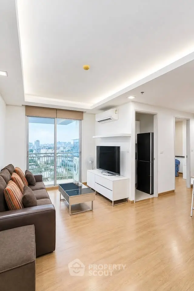 Modern living room with city view, featuring sleek furniture and natural light.