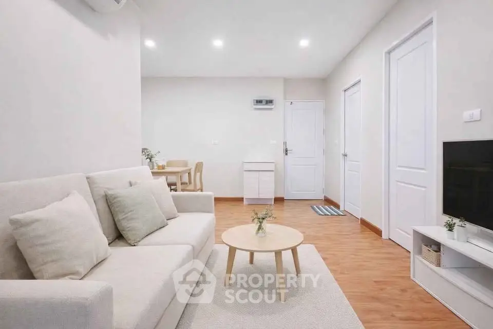 Modern living room with cozy sofa, stylish decor, and wooden flooring in a bright apartment.
