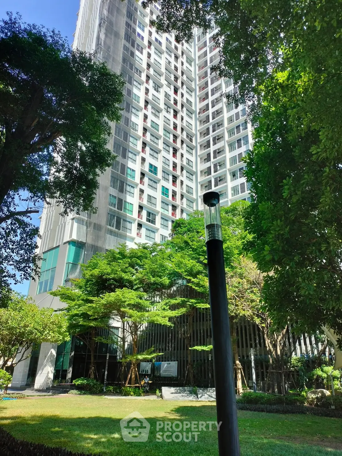 Modern high-rise building surrounded by lush greenery and trees, offering a serene urban living experience.