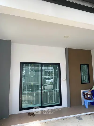 Modern house exterior with stylish sliding glass doors and minimalistic design.