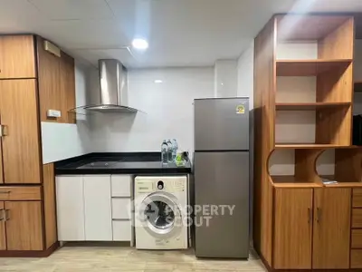 Modern kitchen with wooden cabinets, washing machine, and stainless steel fridge in compact layout.