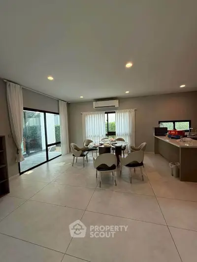 Spacious modern living room with open kitchen and large windows for natural light.