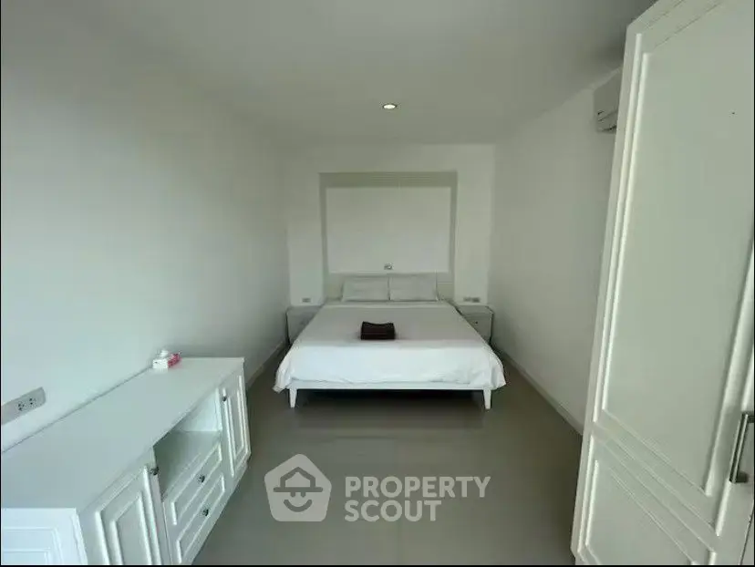Spacious minimalist bedroom with white furniture and modern design.
