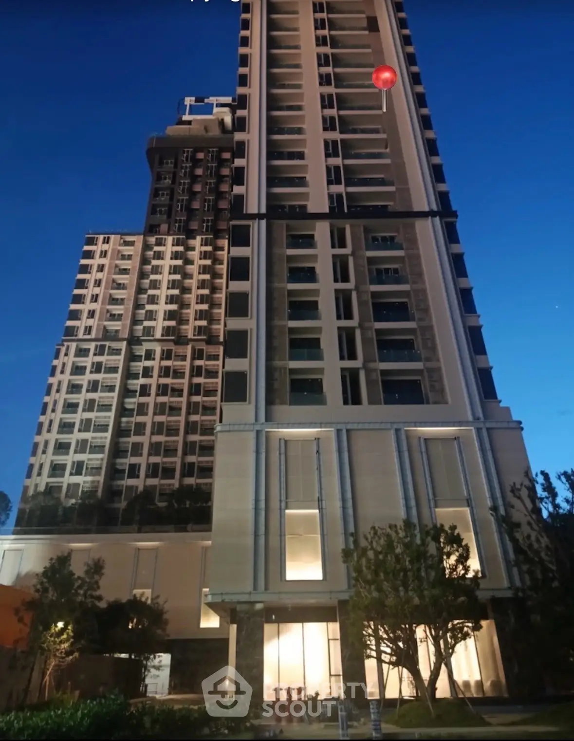 Stunning high-rise building exterior with modern architecture and lush landscaping at dusk.
