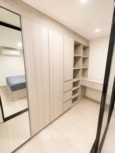 Modern bedroom with built-in wardrobe and mirrored sliding doors, featuring sleek design and ample storage space.