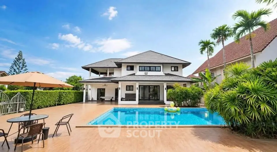 Luxurious villa with private pool and spacious patio, surrounded by lush greenery and palm trees.