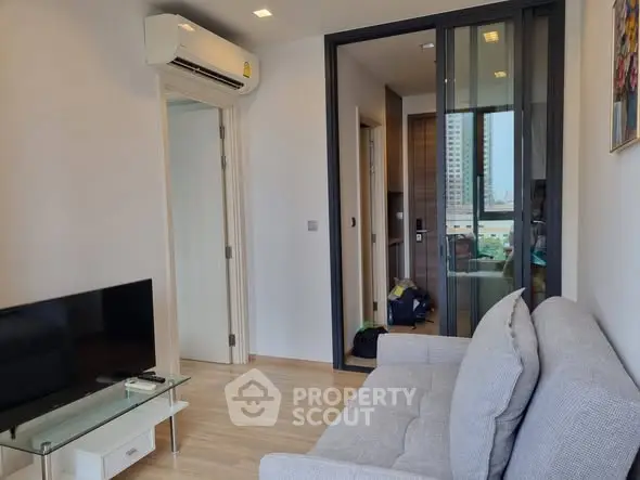 Modern living room with air conditioning and glass door, featuring a cozy sofa and sleek TV setup.