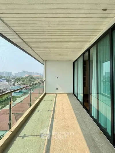 Spacious balcony with city view and glass railing in modern apartment