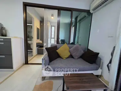 Modern living room with cozy sofa and sliding glass doors leading to a bathroom, featuring contemporary decor.