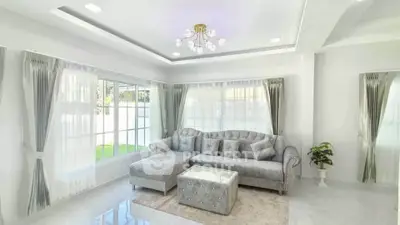 Elegant living room with plush gray sofa and modern chandelier, flooded with natural light.