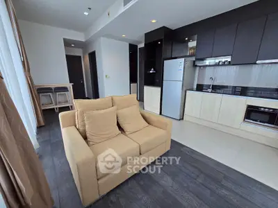 Modern open-layout living room with kitchen, featuring sleek cabinetry and cozy seating area.