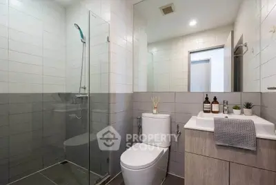 Modern bathroom with glass shower and sleek fixtures in contemporary apartment.