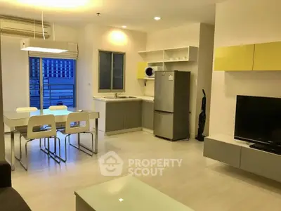 Modern open-layout living room and kitchen with sleek furniture and appliances.