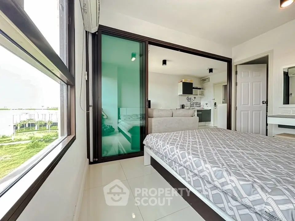 Modern bedroom with glass partition and sleek kitchen view