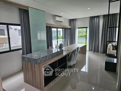 Modern open-plan living room with sleek marble countertops and large windows.