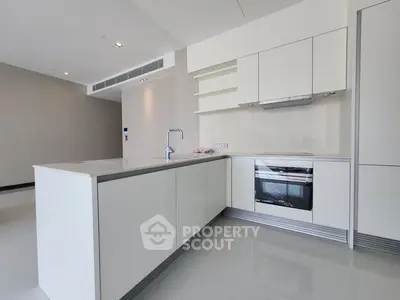 Modern kitchen with sleek white cabinetry and built-in oven in a contemporary apartment.