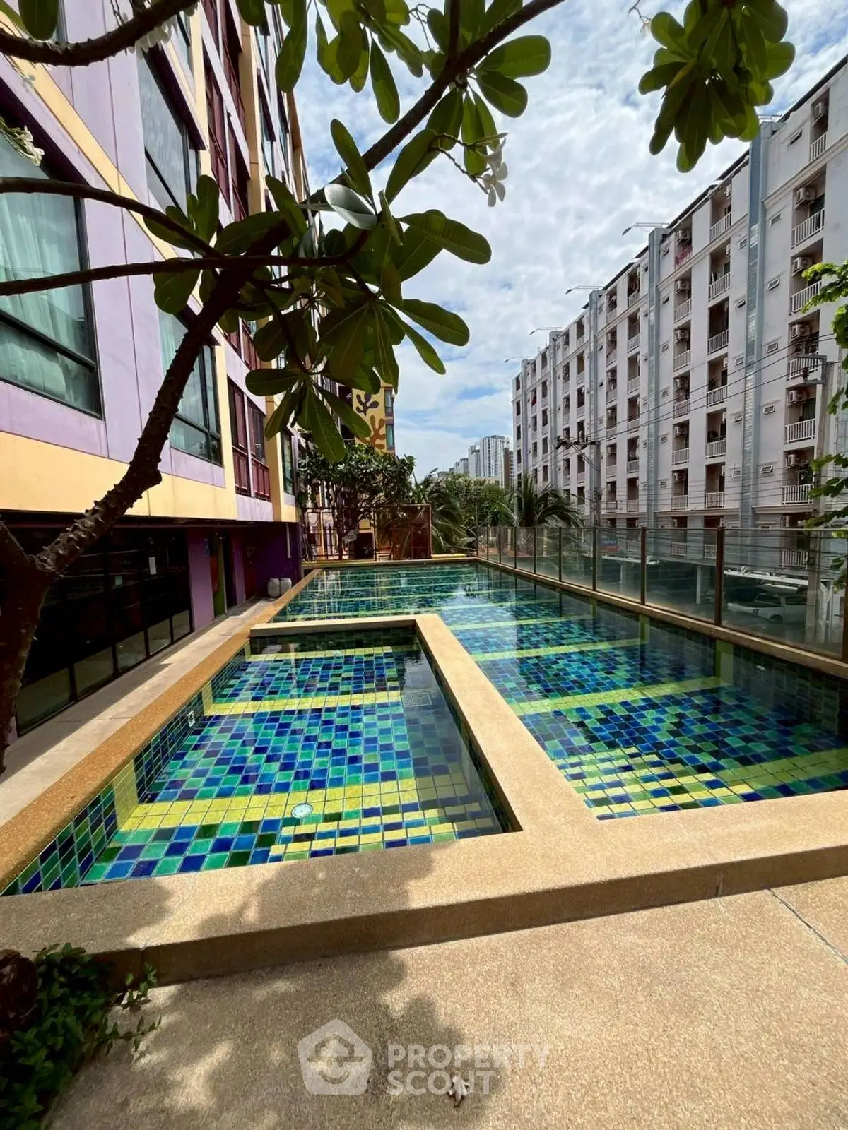 Stunning pool area in modern apartment complex with vibrant mosaic tiles and lush greenery.
