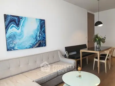 Modern living room with stylish decor and abstract art, featuring a cozy sofa and elegant dining area.