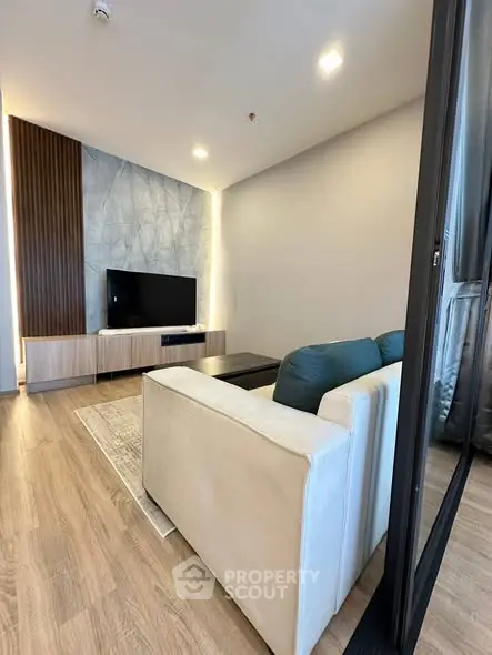 Modern living room with stylish decor and flat-screen TV, featuring wood flooring and contemporary furniture.