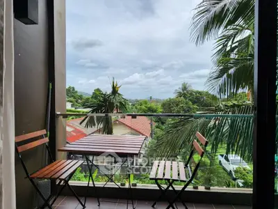 Charming balcony with lush green view and cozy seating area, perfect for relaxation.