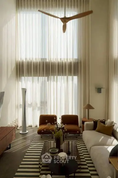 Luxurious living room with high ceilings, modern furniture, and large windows for natural light.