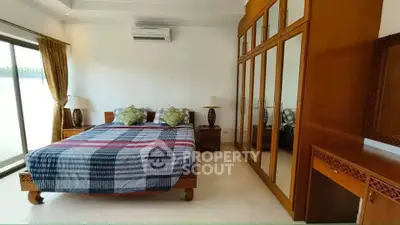Spacious bedroom with large mirrored wardrobe and natural light from sliding glass doors.