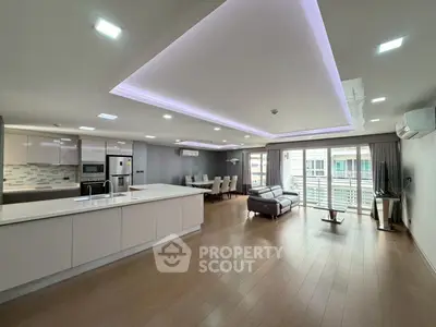 Spacious modern living room with open kitchen and balcony access, featuring sleek design and ample natural light.