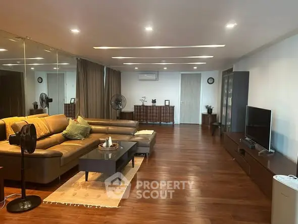 Spacious modern living room with sleek wooden flooring and stylish furniture.