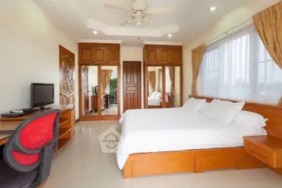Spacious bedroom with elegant wooden furniture and large windows for natural light.