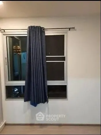 Minimalist room with window and blue curtains, ideal for cozy living space.