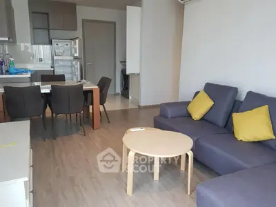 Modern living room with open kitchen, stylish furniture, and wooden flooring in a cozy apartment.