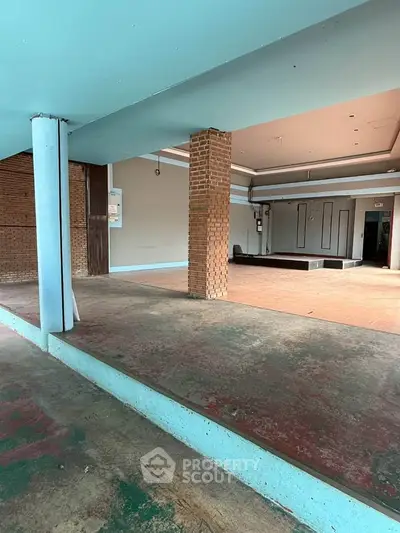 Spacious open-plan interior with brick accents and elevated platform, ideal for versatile use.