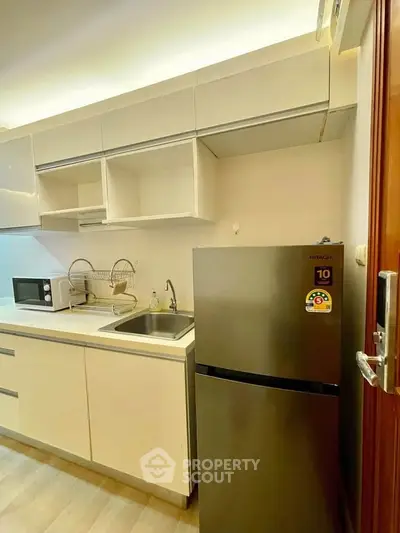 Modern kitchen with sleek cabinetry and stainless steel fridge in a cozy apartment.