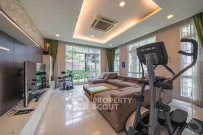 Spacious living room with modern fitness equipment and large windows overlooking garden