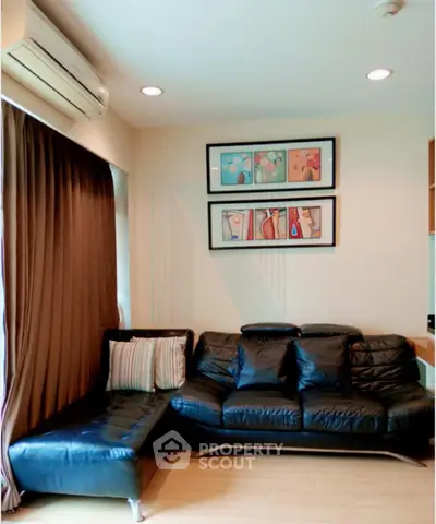 Stylish living room with black leather sofa and modern art decor, featuring cozy ambiance and natural light.