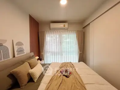 Cozy bedroom with modern decor and natural light from large window.