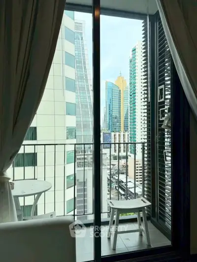 Stunning city view from a modern apartment balcony with sleek glass doors.