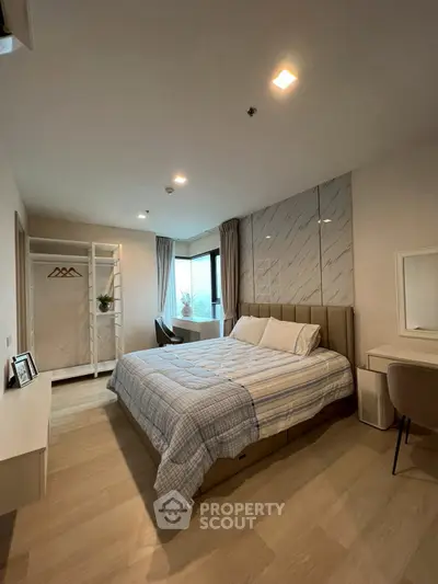 Spacious bedroom with modern decor and large windows offering natural light.