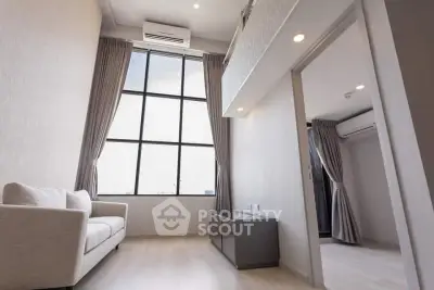 Modern living room with high ceiling and large window, featuring a cozy sofa and sleek design.