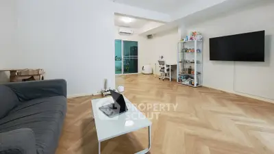 Spacious modern living room with sleek furniture and large TV, perfect for relaxation and entertainment.